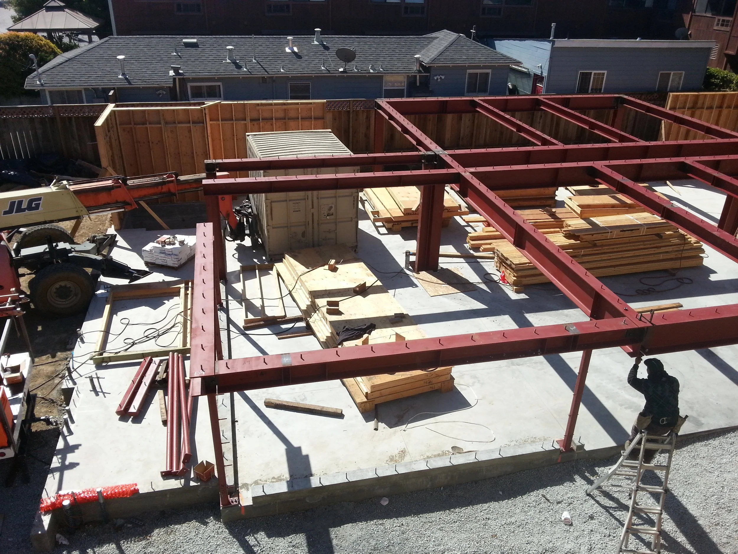Heavy-duty red steel beams forming the backbone of a reinforced foundation—engineered to support four new apartments above.