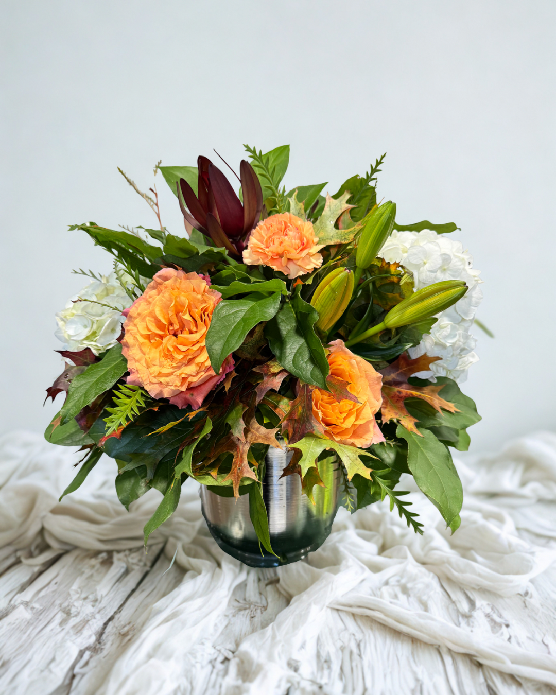 White hydrangea flowers in a black and white vase on a white table in a modern interior.
