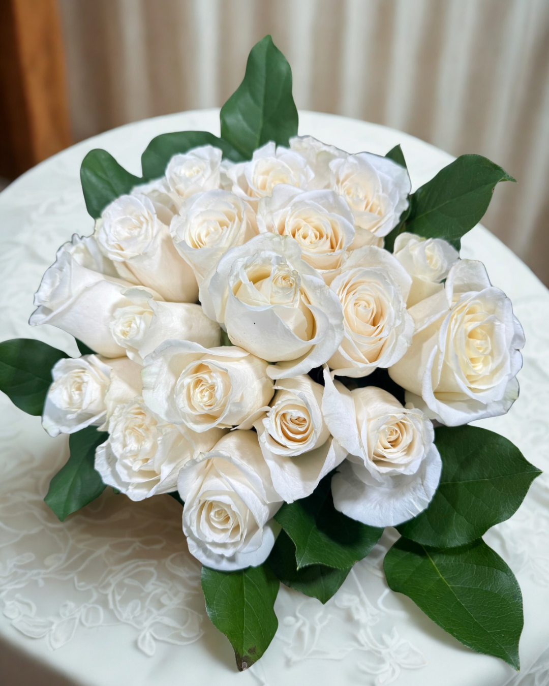 Bride holding a bouquet of white roses, baby's breath, and eucalyptus leaves.