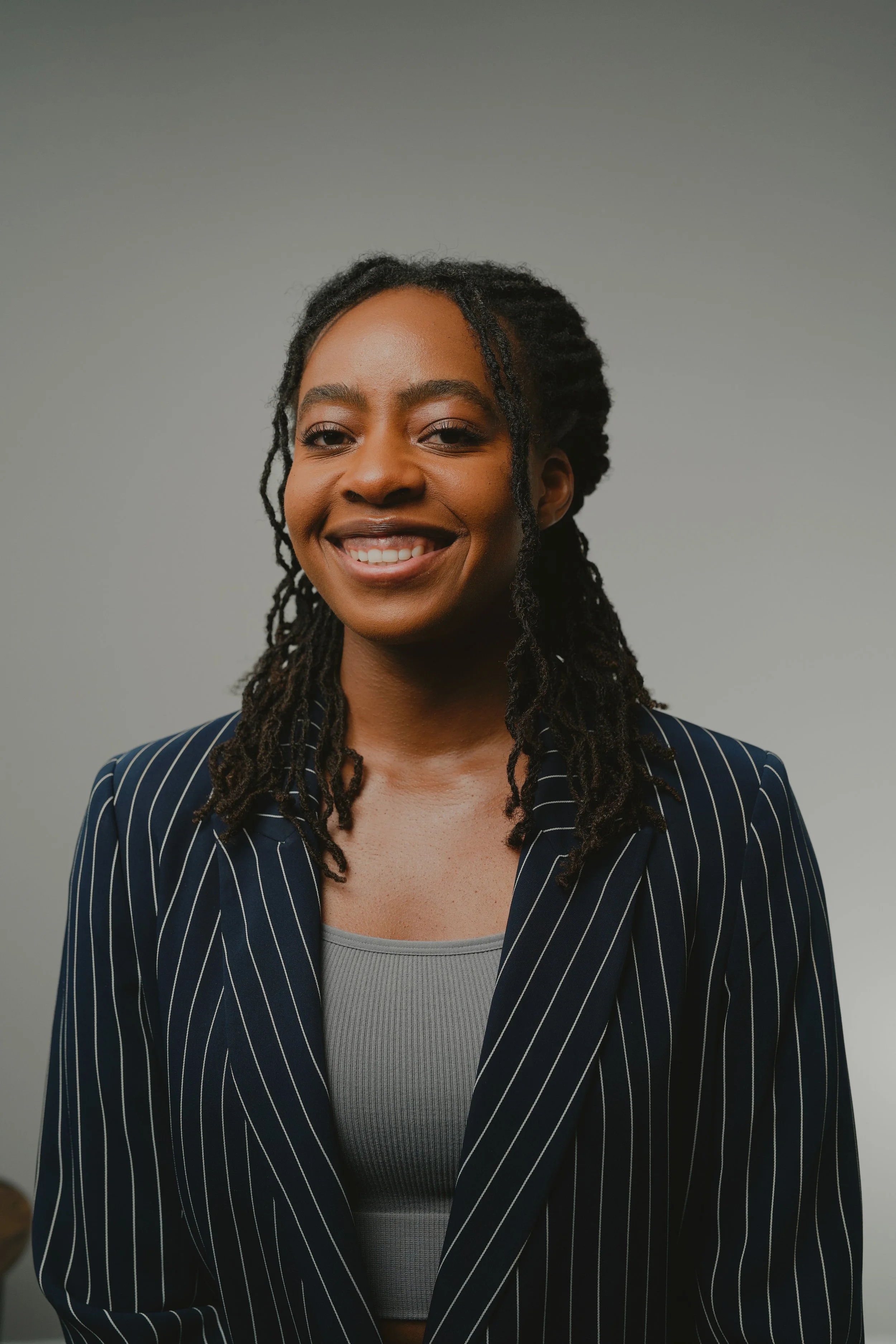 a woman wearing a black striped suite smiling at the camera