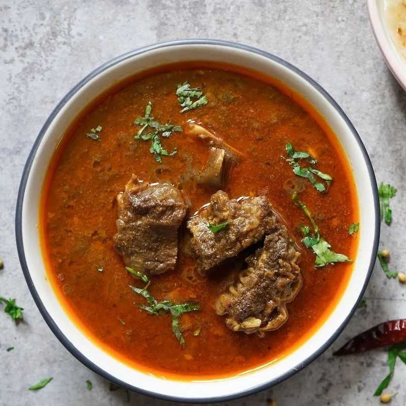Rich goat meat stew with tender stew meat in a spiced broth, garnished with fresh cilantro — ranch-direct goat meat from Dry Creek Pastures.