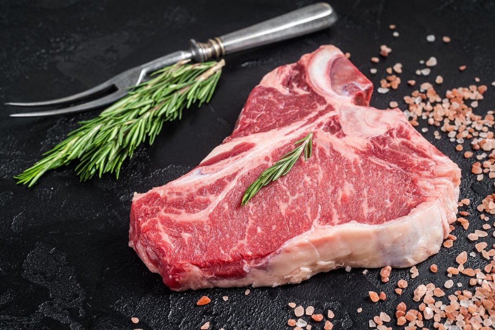Raw T-bone steak with fresh rosemary and pink salt — ranch-direct beef shares from Dry Creek Pastures.