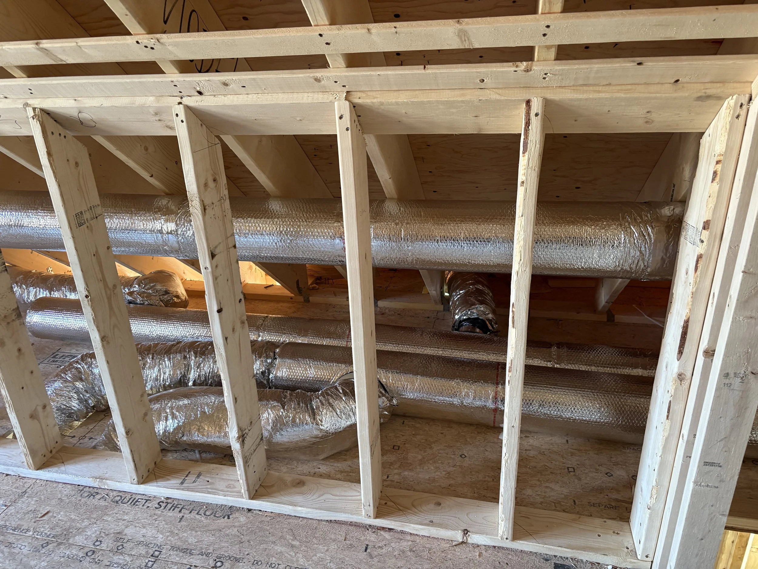 View of building interior framing with exposed wooden studs and HVAC ductwork.