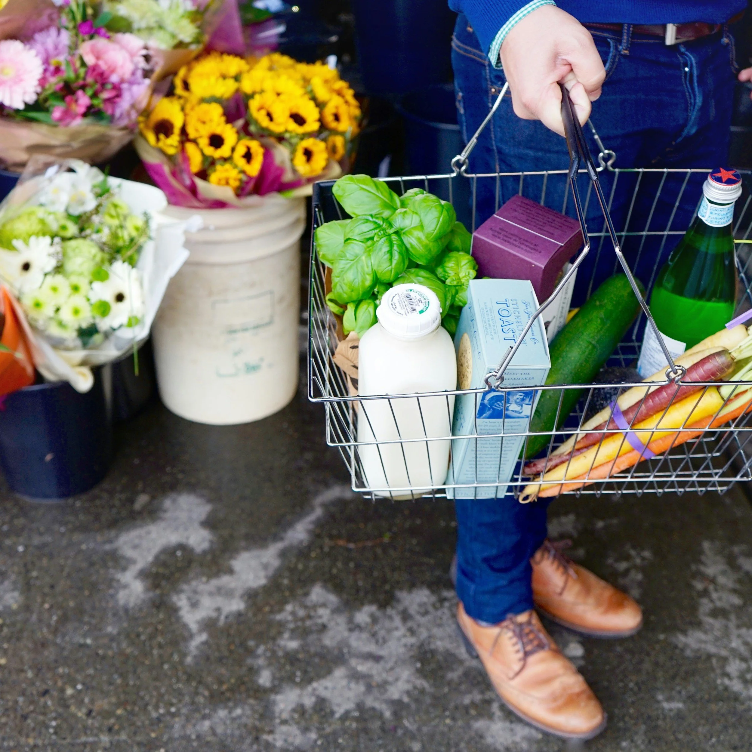 Image of a person holding a handbasket of groceries, cropped at the waist