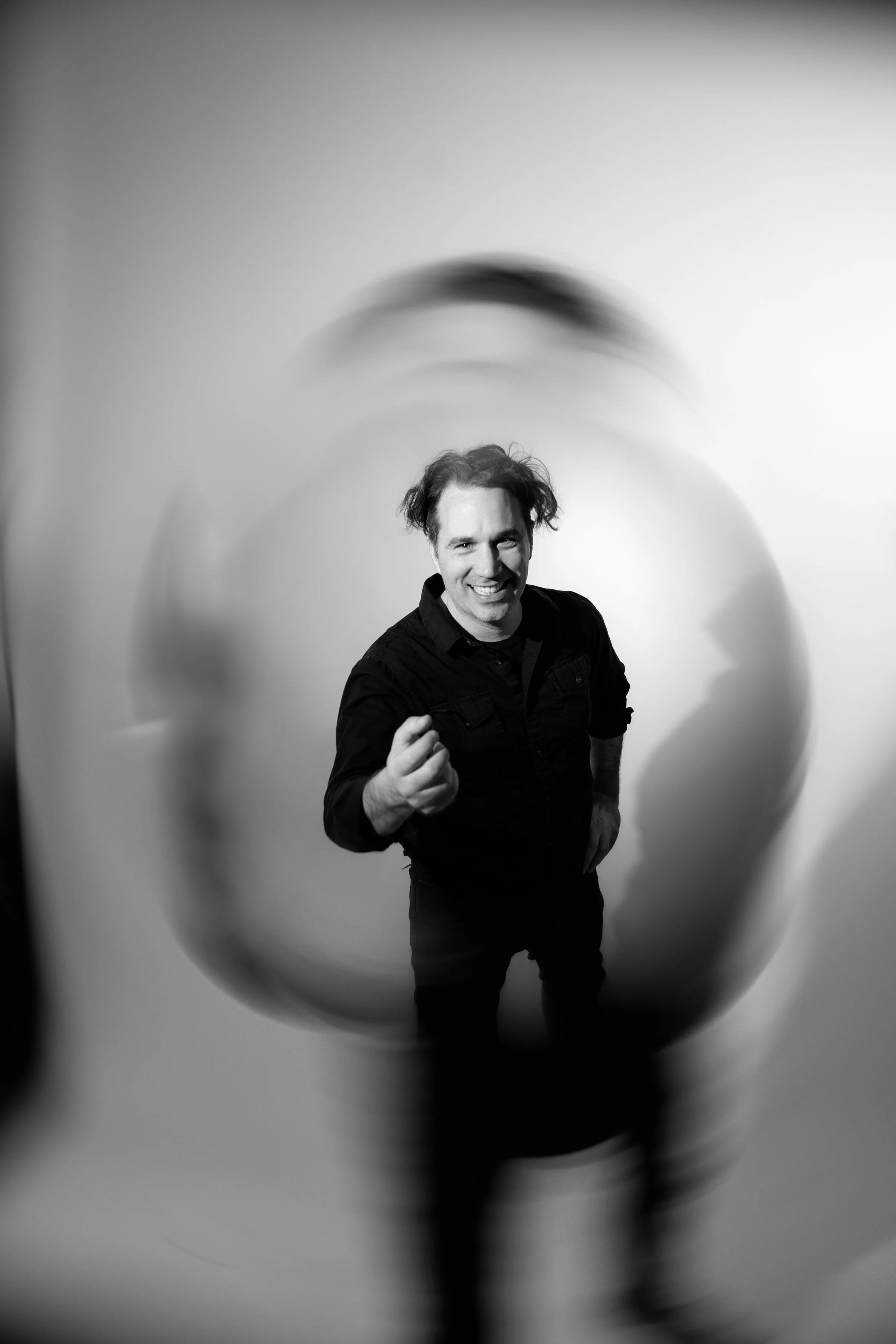 John Godfrey, owner and DJ of Party People and Sons, pointing towards the camera, seen through a reflective, rounded surface that distorts the image.