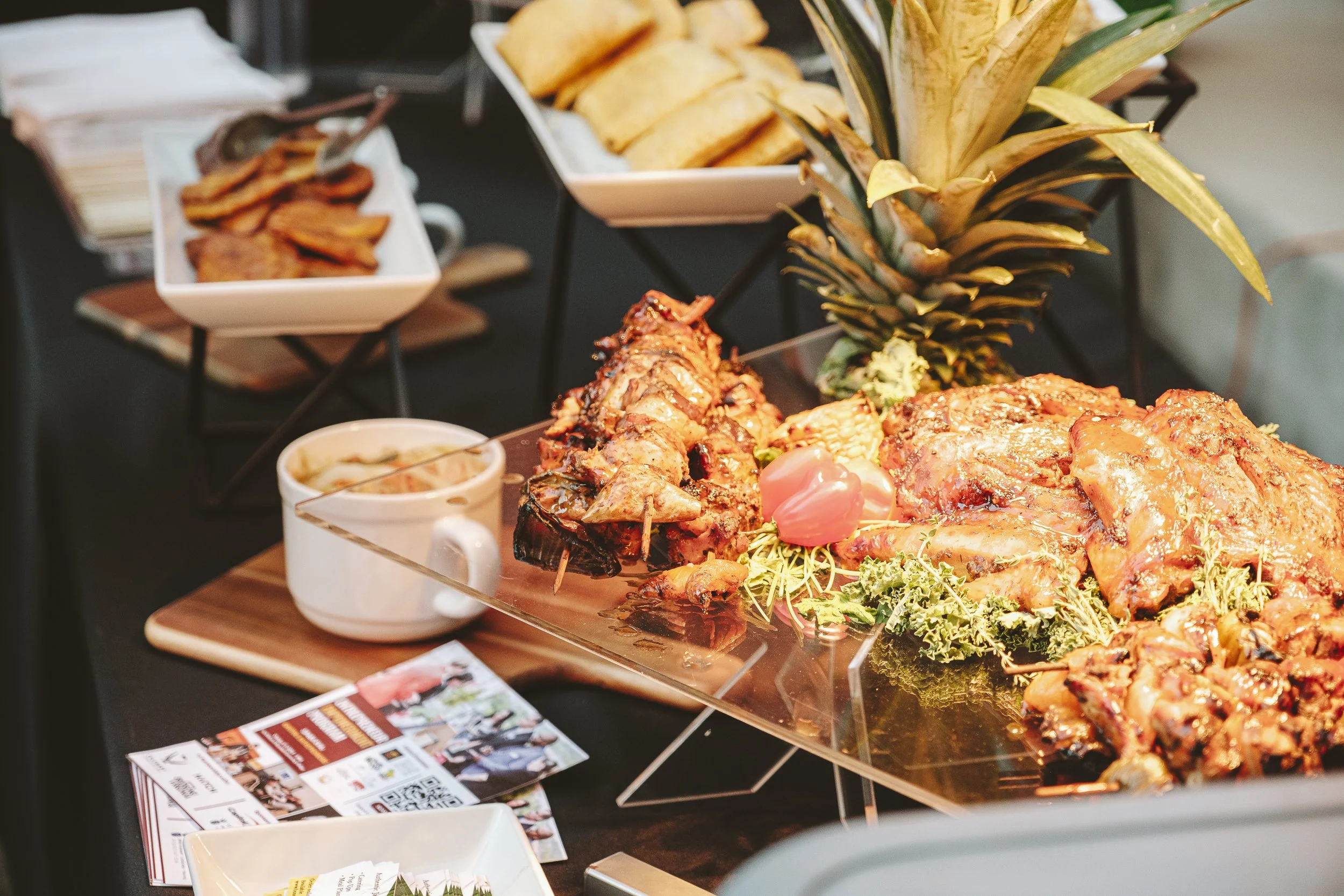 Buffet with roasted meat, pineapple, chips, and sliced bacon.