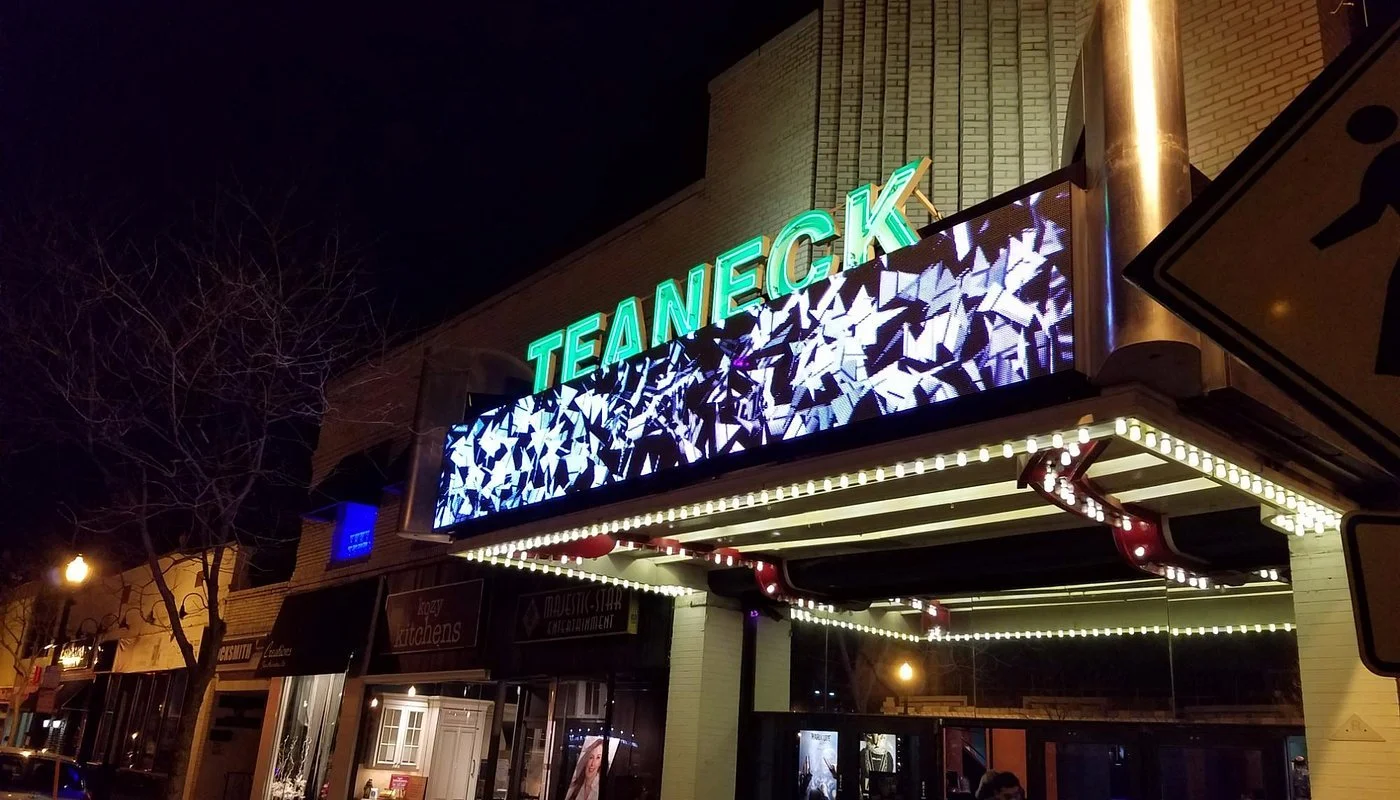Nighttime view of a theater marquee with green illuminated lights in Teaneck, NJ. JordyClean offers medical office and commercial cleaning services in Teaneck, New Jersey