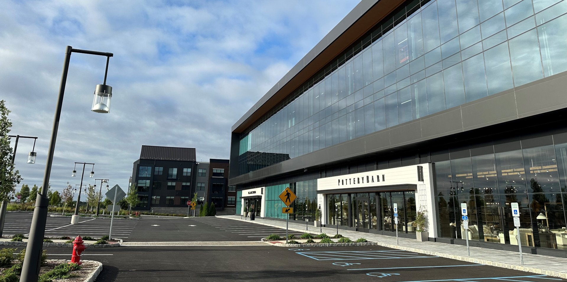 Modern commercial building with glass facade and a sign that reads Pottery Barn in Montvale, New Jersey. An empty parking lot with designated handicapped spots.. JordyClean provides office and medical office cleaning in Montvale, New Jersey.