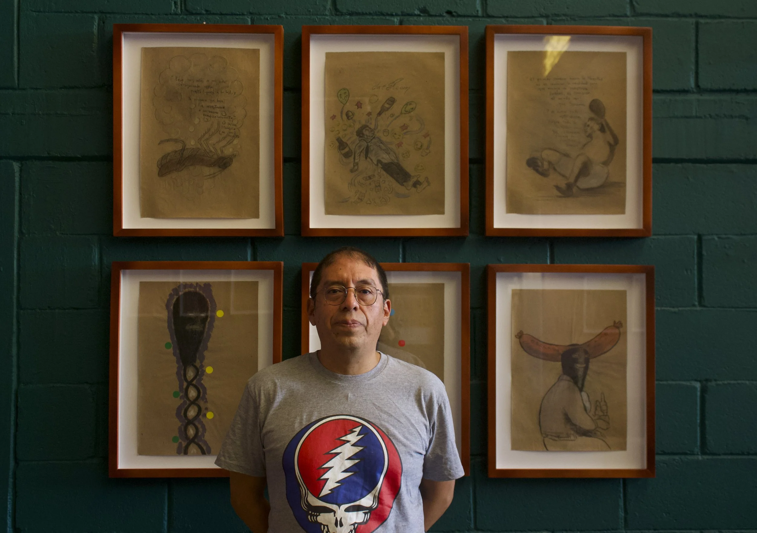 El artista Daniel Guzmàn junto con 6 de los dibujos que conforman la muestra La Modernidad Insufrible, dibujos de segunda mano.