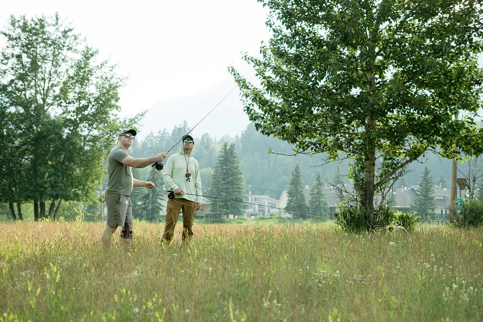 A man making a cast in the grass with a guide stood next to him