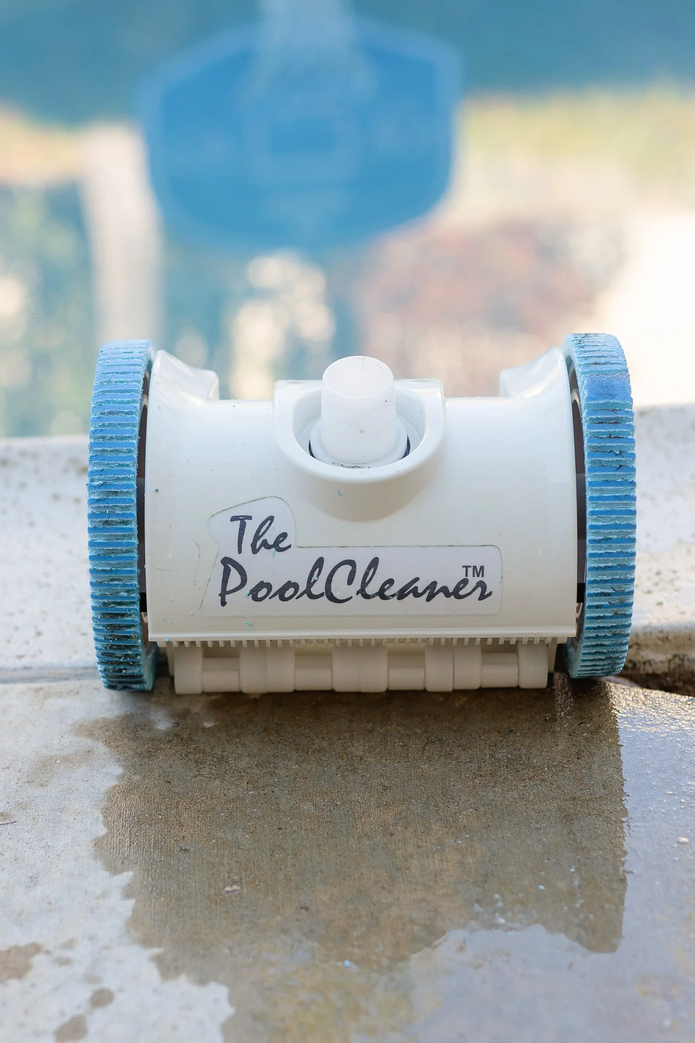 A Pool Vacuum Cleaner with old, ruined Wheels on a pool deck