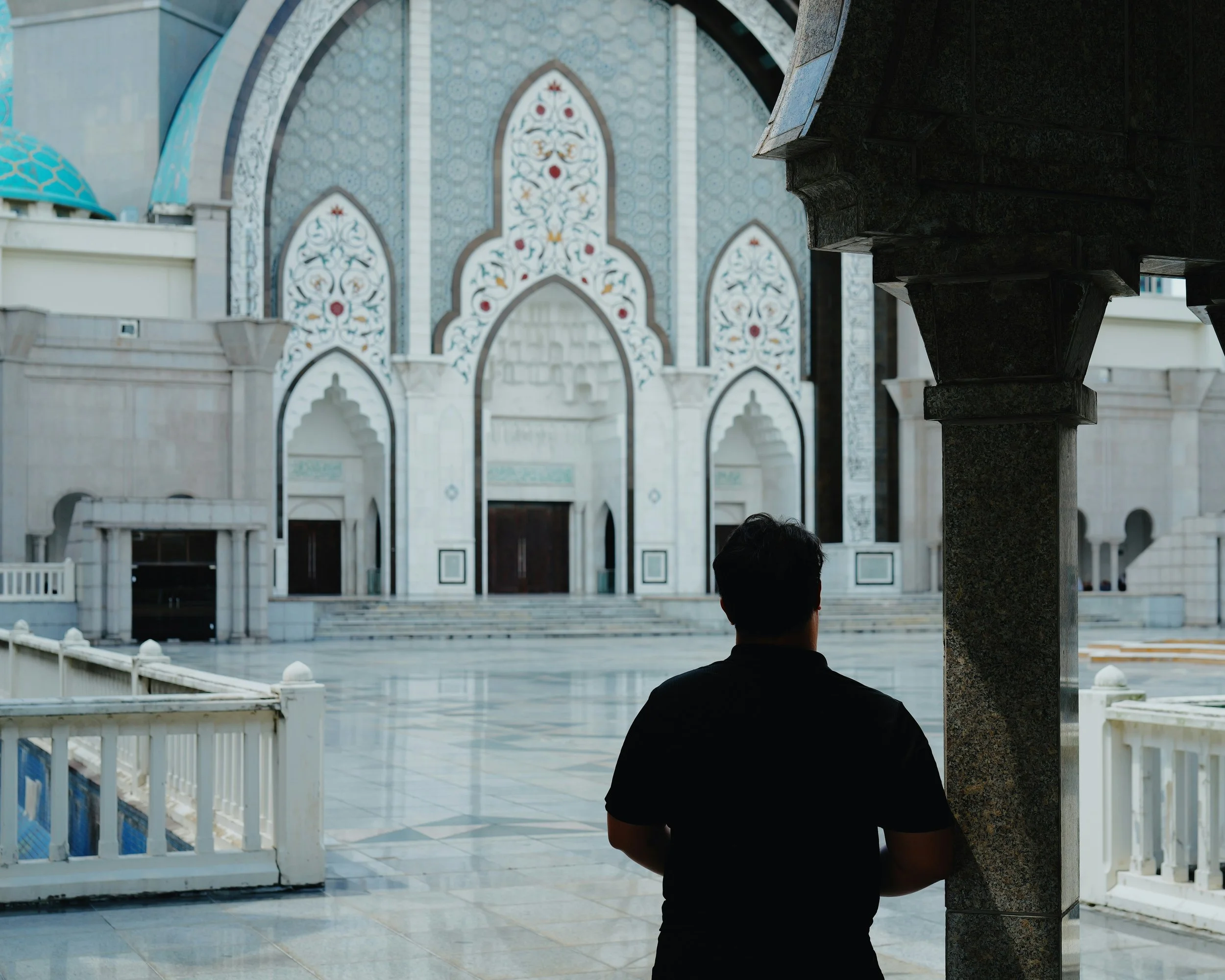 A person standing alone at the entrance of a mosque