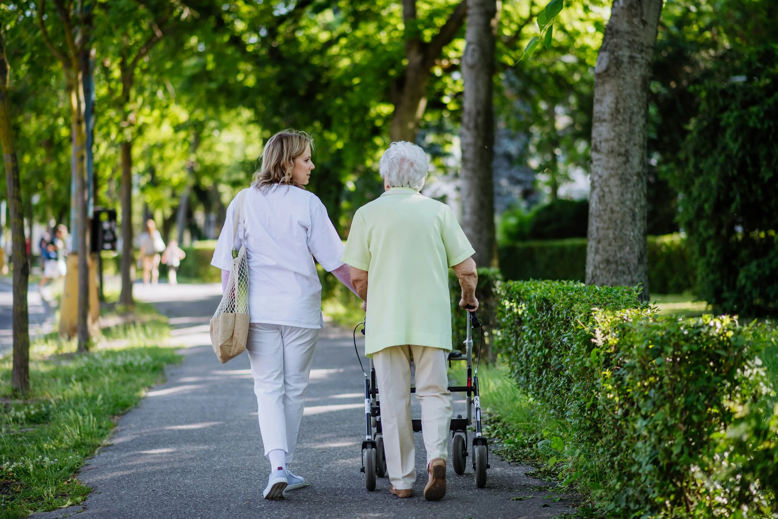 An adult child helping an elderly parent walk