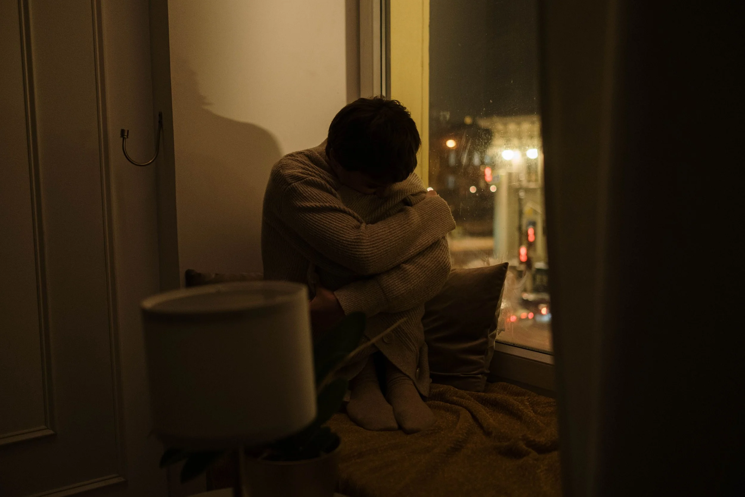 student sitting alone in dorm room with head down