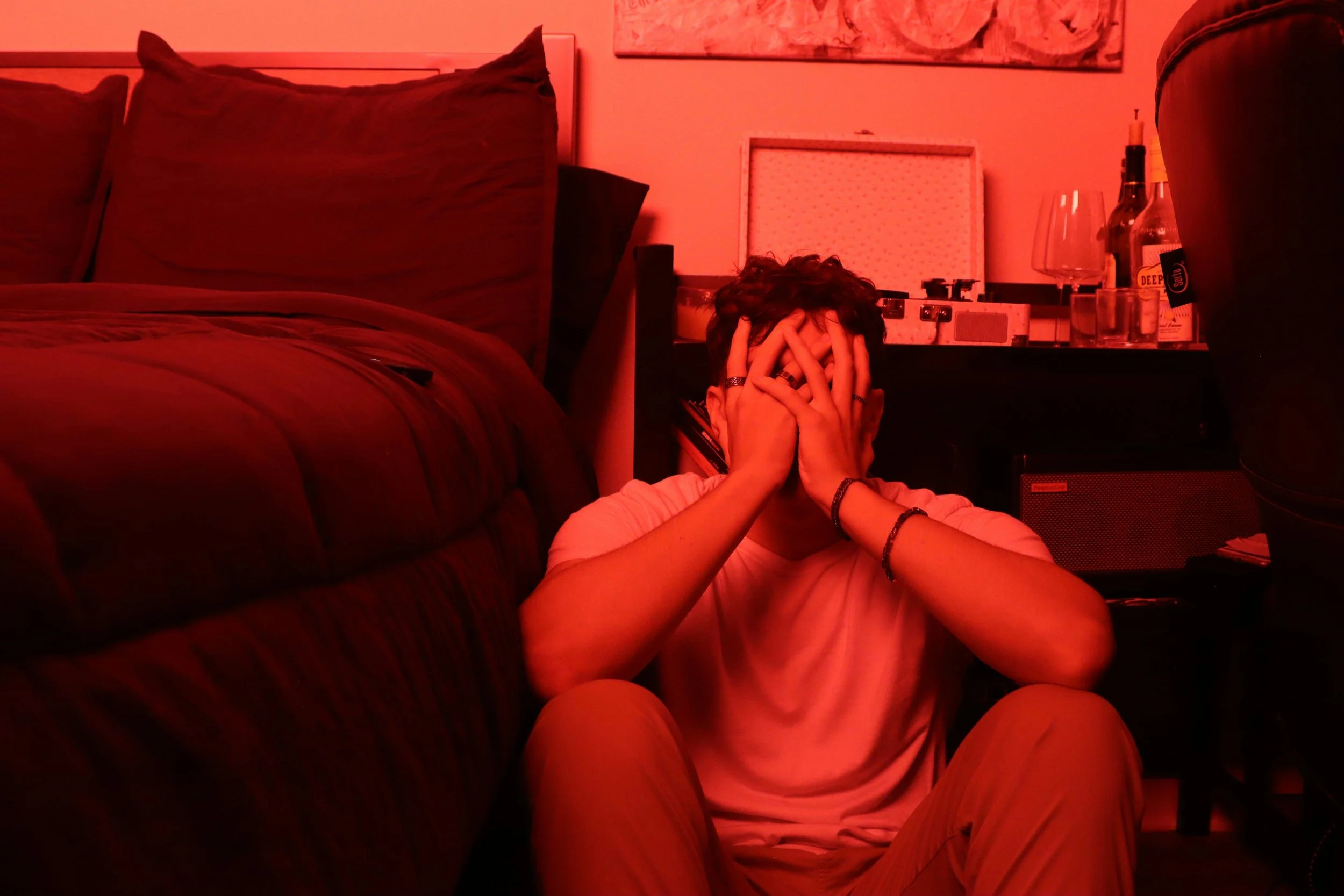An adult sitting on the edge of a bed late at night, head in hands
