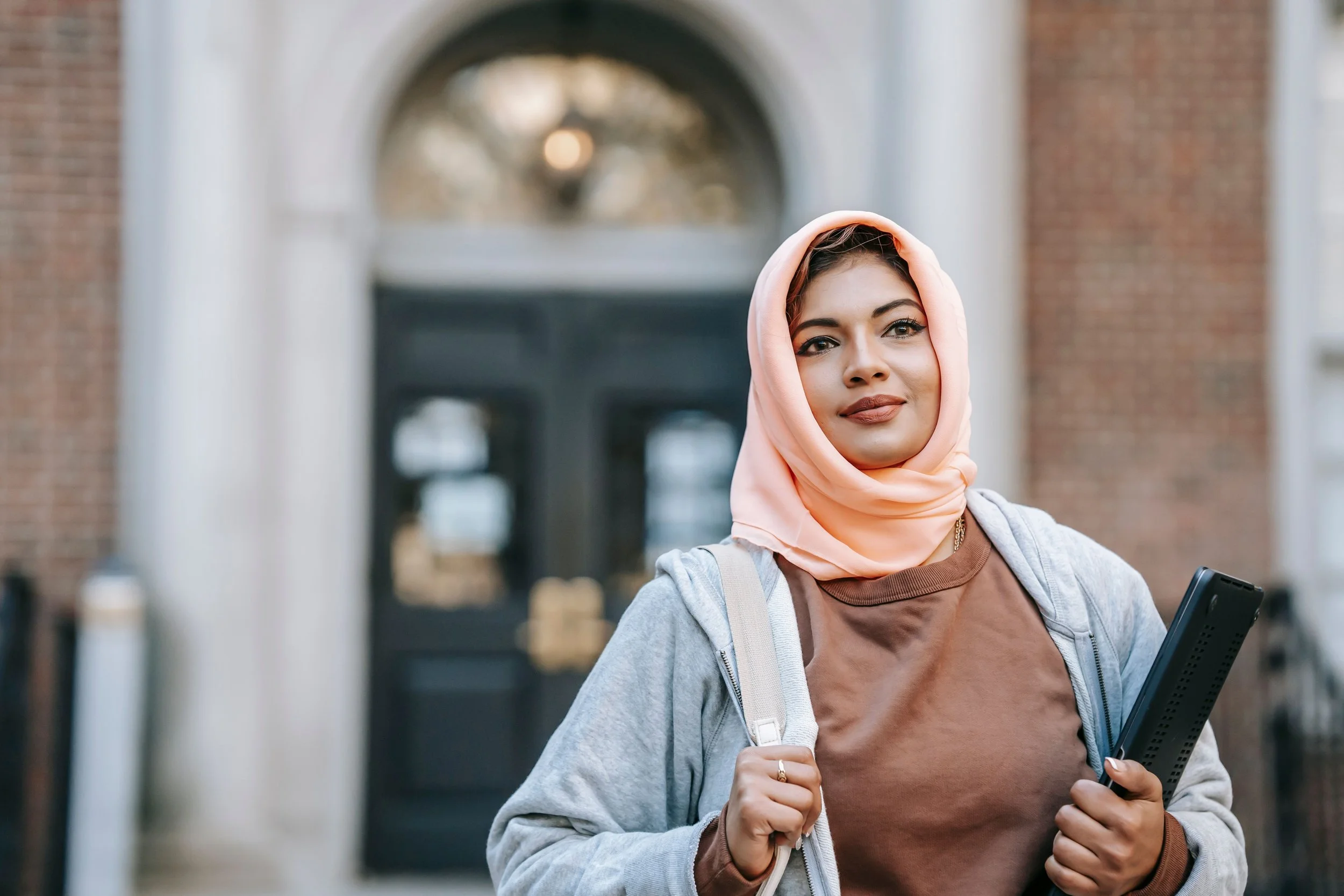 A Muslim student standing outside a university building