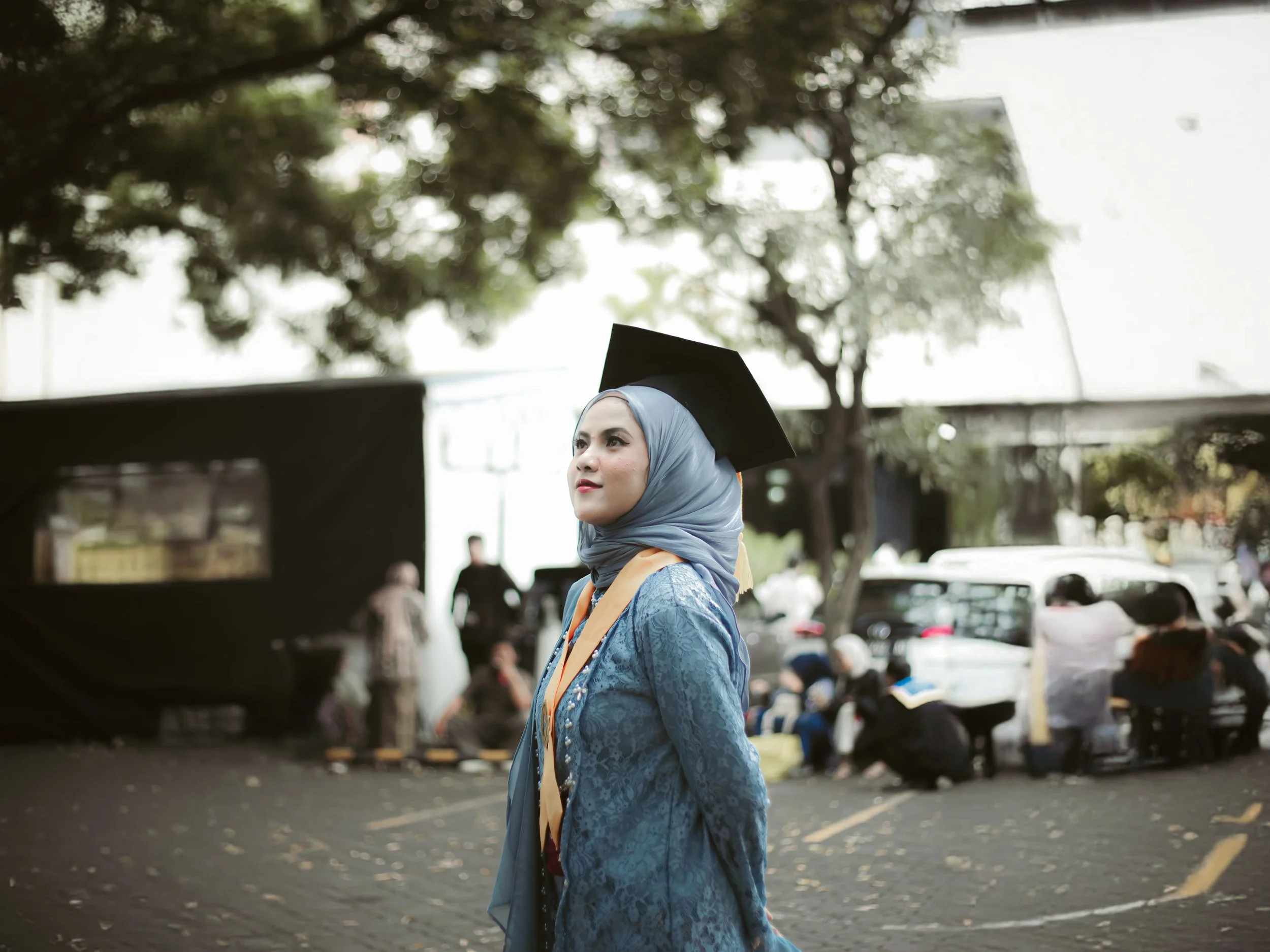Young woman in hijab wearing graduation cap, standing outdoors