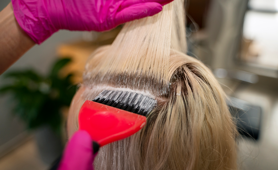 Professional showing two color-treated hair samples—red and blonde—demonstrating hair coloring terms and techniques like single- and double-process application.