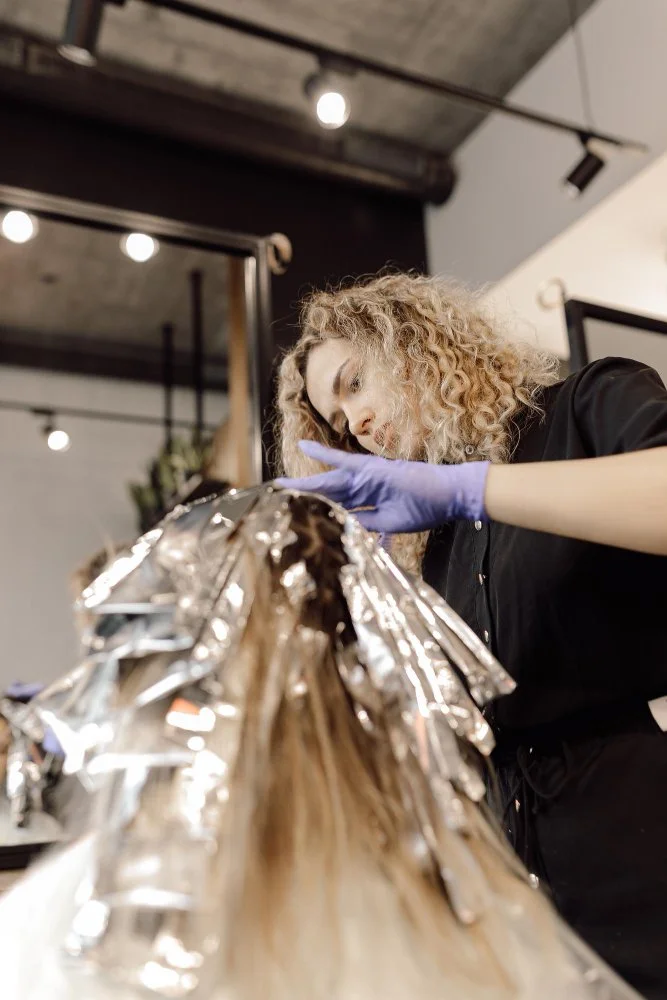 Salon colorist applying foils during a balayage touch-up appointment in a Chicago hair salon.