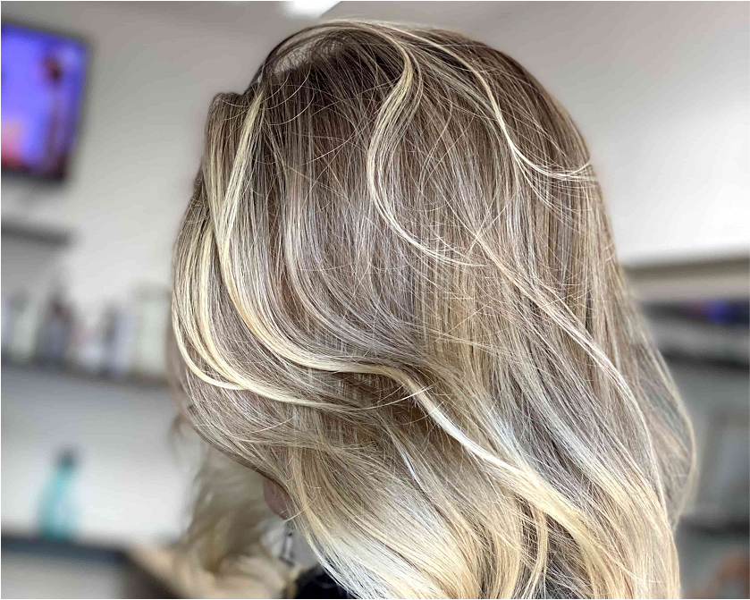 Long blonde waves fall softly past the shoulders with subtle dimension