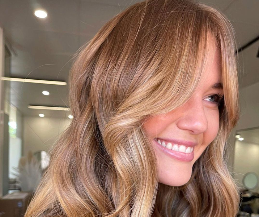 Best hair colorist in Chicago applying color to a client's brown hair in front of a salon mirror.