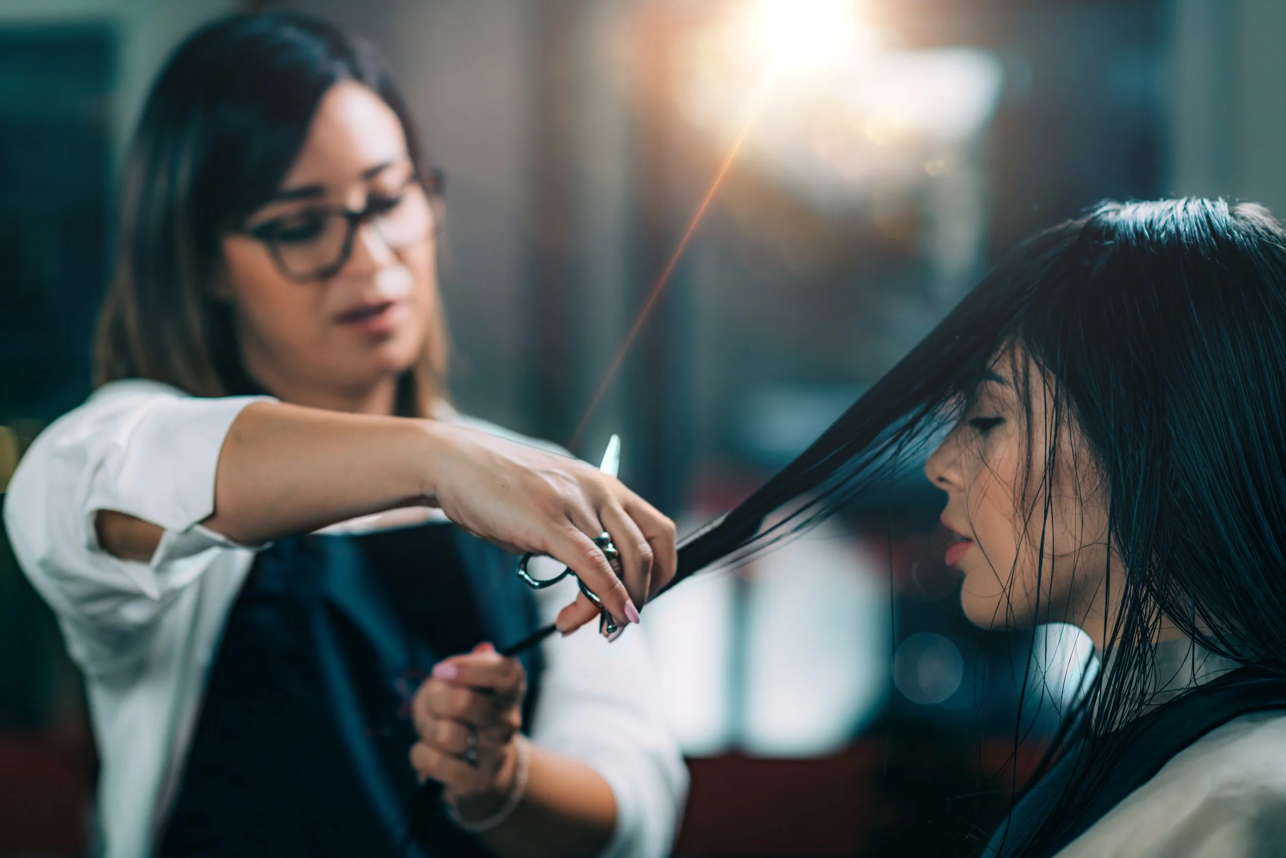 A stylist sectioning a client's dark hair, part of a hair salon consultation.
