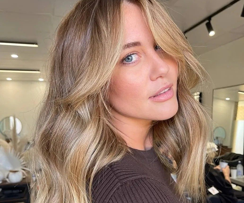 Smiling client receiving hair coloring services in a Chicago salon, applying gray dye with a brush.