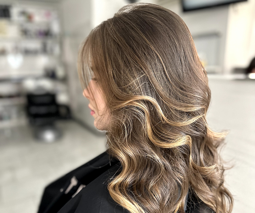 Close-up of a client's finished balayage result showing soft, sun-kissed dimension and natural grow-out at a hair color salon.