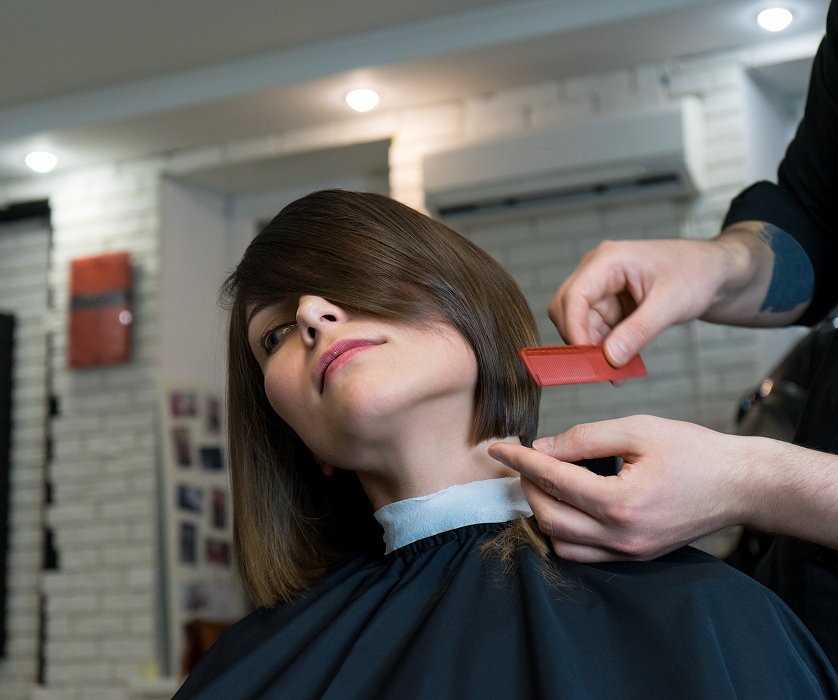 Client receiving a precise fringe trim while seated in a salon chair.