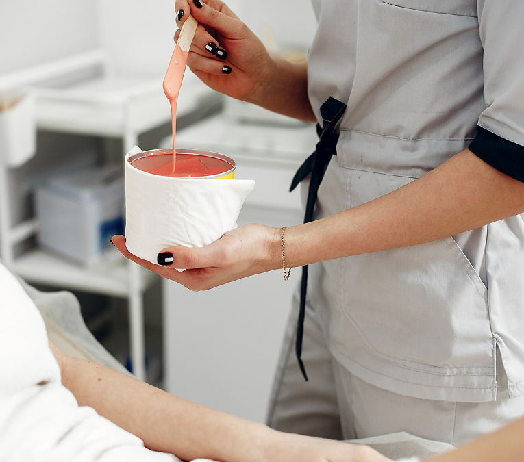 Waxing salon Chicago esthetician in pink gloves applying wax to a client's stomach with a spatula.