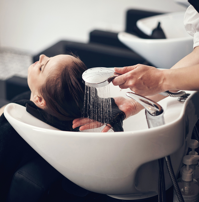 Client relaxing at the shampoo bowl while the stylist performs a soothing salon scalp massage.