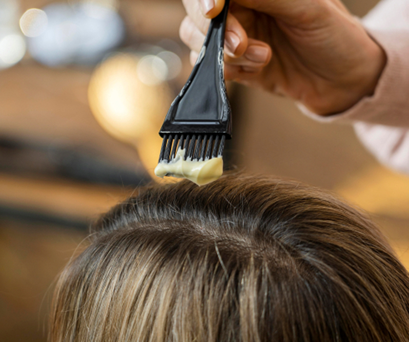 Close-up of a colorist working on a client's hair during a balayage application at a salon.