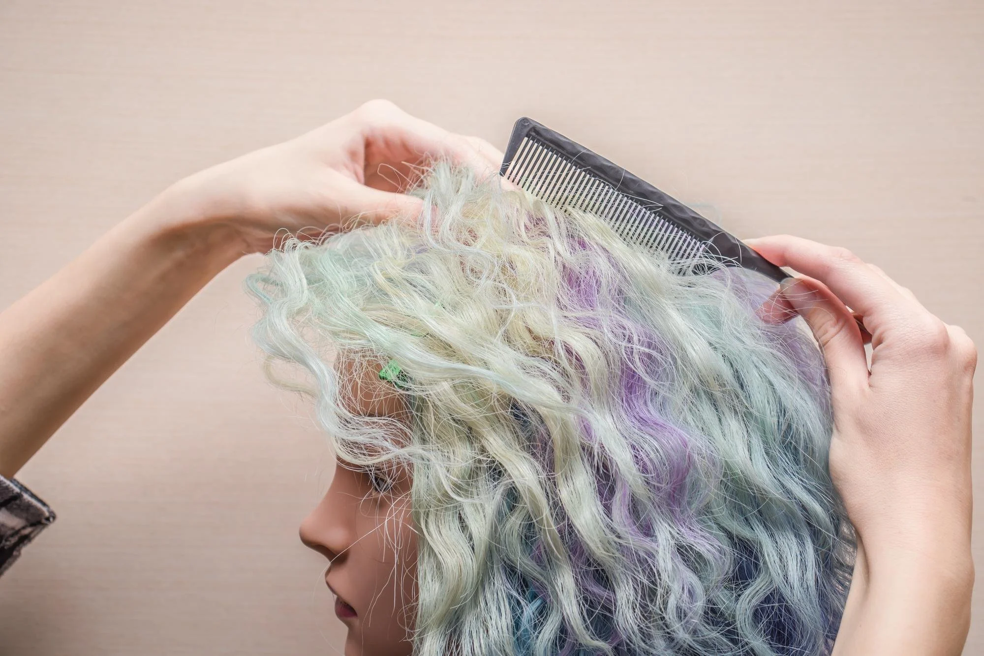Stylist carefully applies pastel-toned color to textured hair using a comb to showcase a safe hair dye for a sensitive scalp