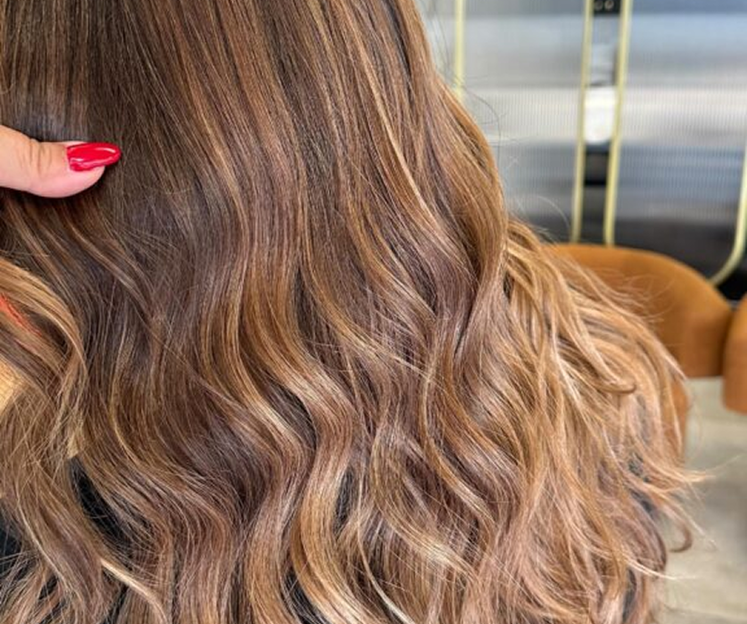 Hair color specialist in Chicago reviewing a color swatch chart with a client at a salon mirror.