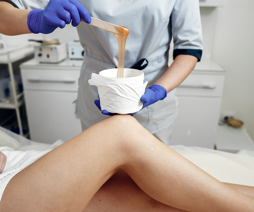 Smiling client in a robe receiving body waxing Chicago treatment on a spa bed.