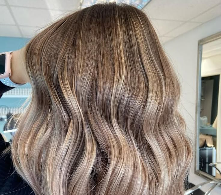 Hair color specialist in Chicago reviewing a color swatch book with a client in a salon chair.