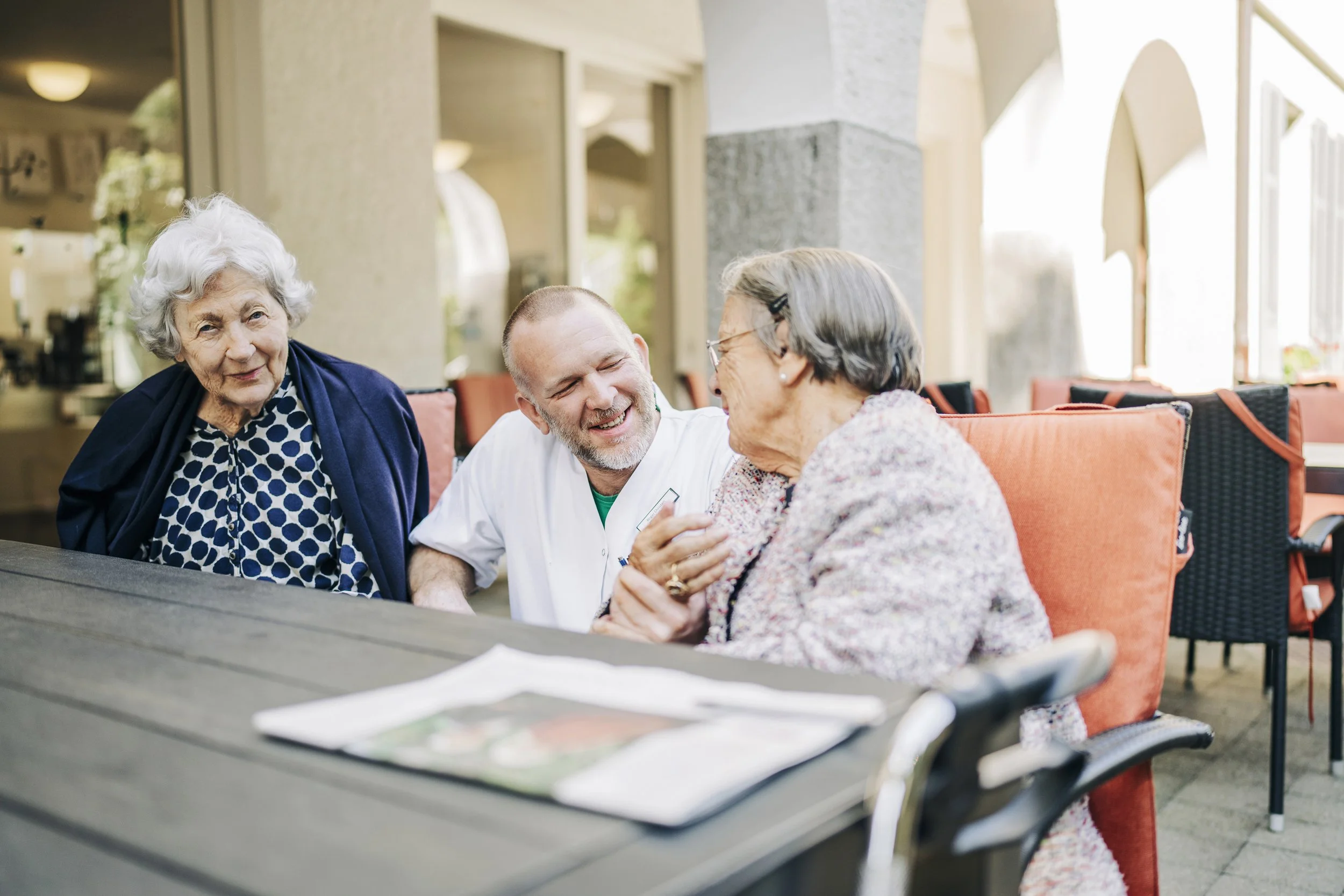 Pflegepersonal unterhält sich freundlich mit älterer Dame in einem Pflegeheim oder Seniorenheim.