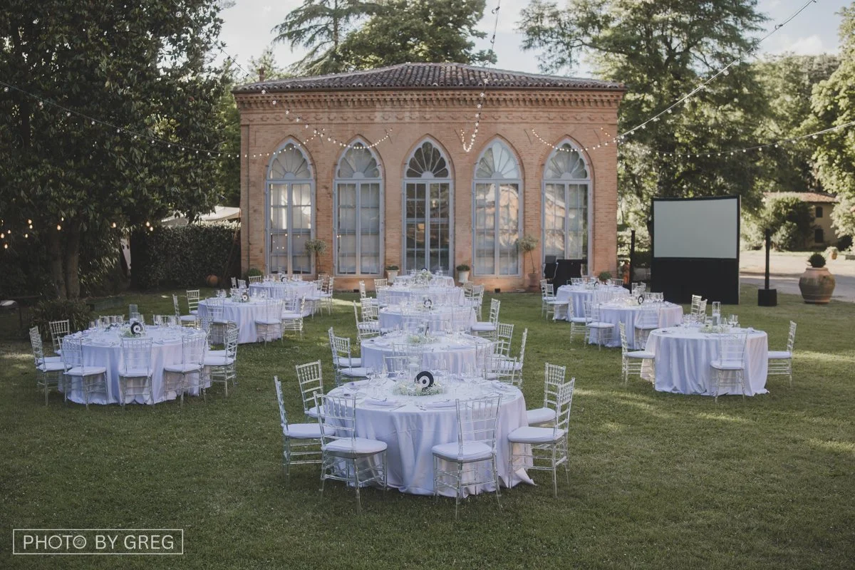 Il giardino della location del matrimonio con tavoli imbanditi. centrotavola floreali con dischi in vinile per un tema musica. Un allestimento elegante e pulito. 