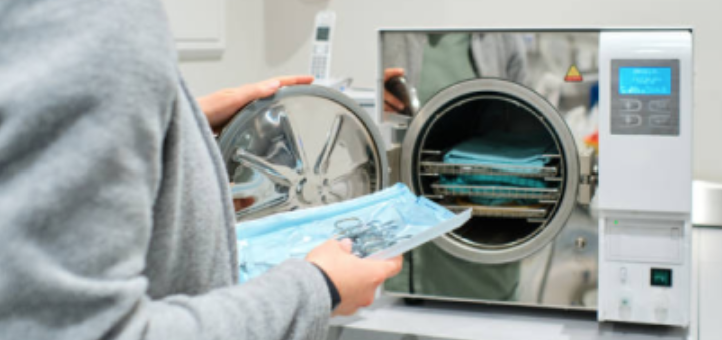 Person inserting a tray of surgical tools into an autoclave sterilizer.
