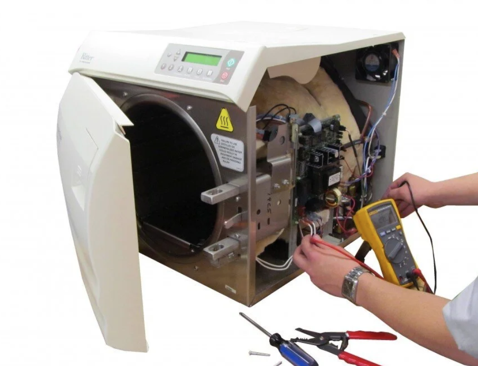 Technician repairing household washing machine with multimeter and tools.