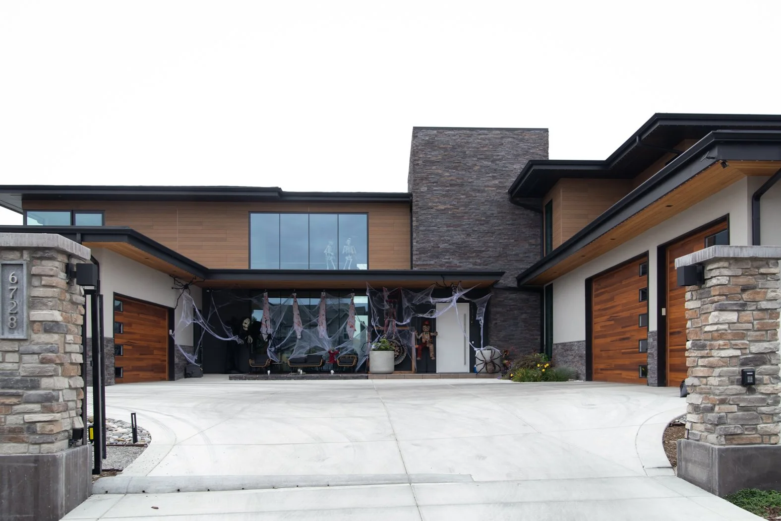 Modern house decorated with Halloween decorations including skeletons, spider webs, and skeleton mannequins. Roofing Company in Denver Colorado