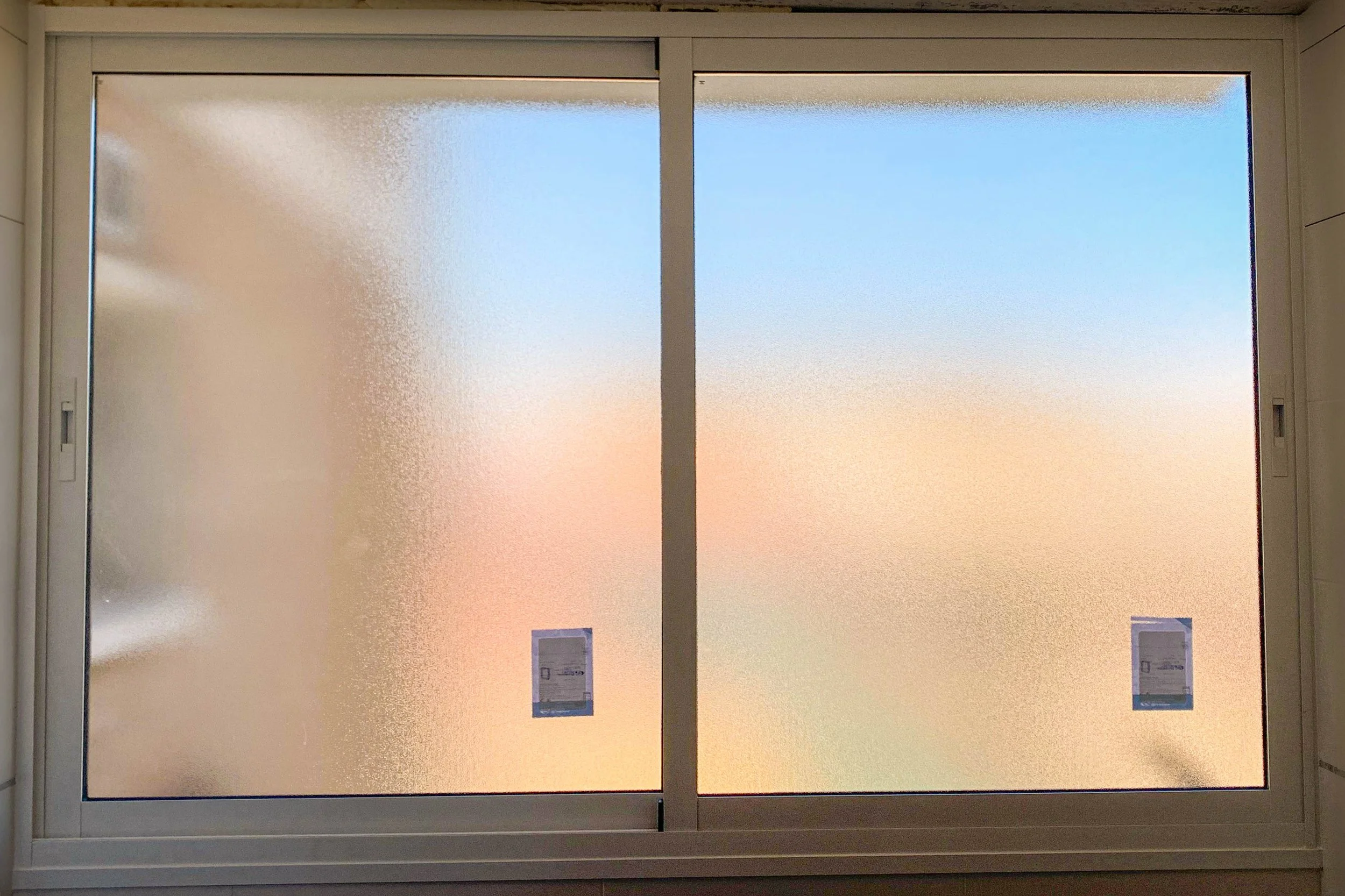 Ventana de aluminio de dos hojas correderas con vidrio Climalit translúcido para mayor intimidad, aislamiento térmico y aislamiento sonoro.
Con techo exterior anti-lluvia.