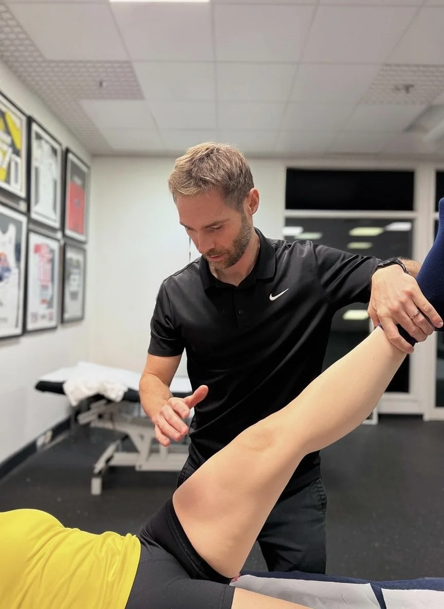 A physiotherapist carrying out Be Activated techniques on a patient's leg in a clinical setting.