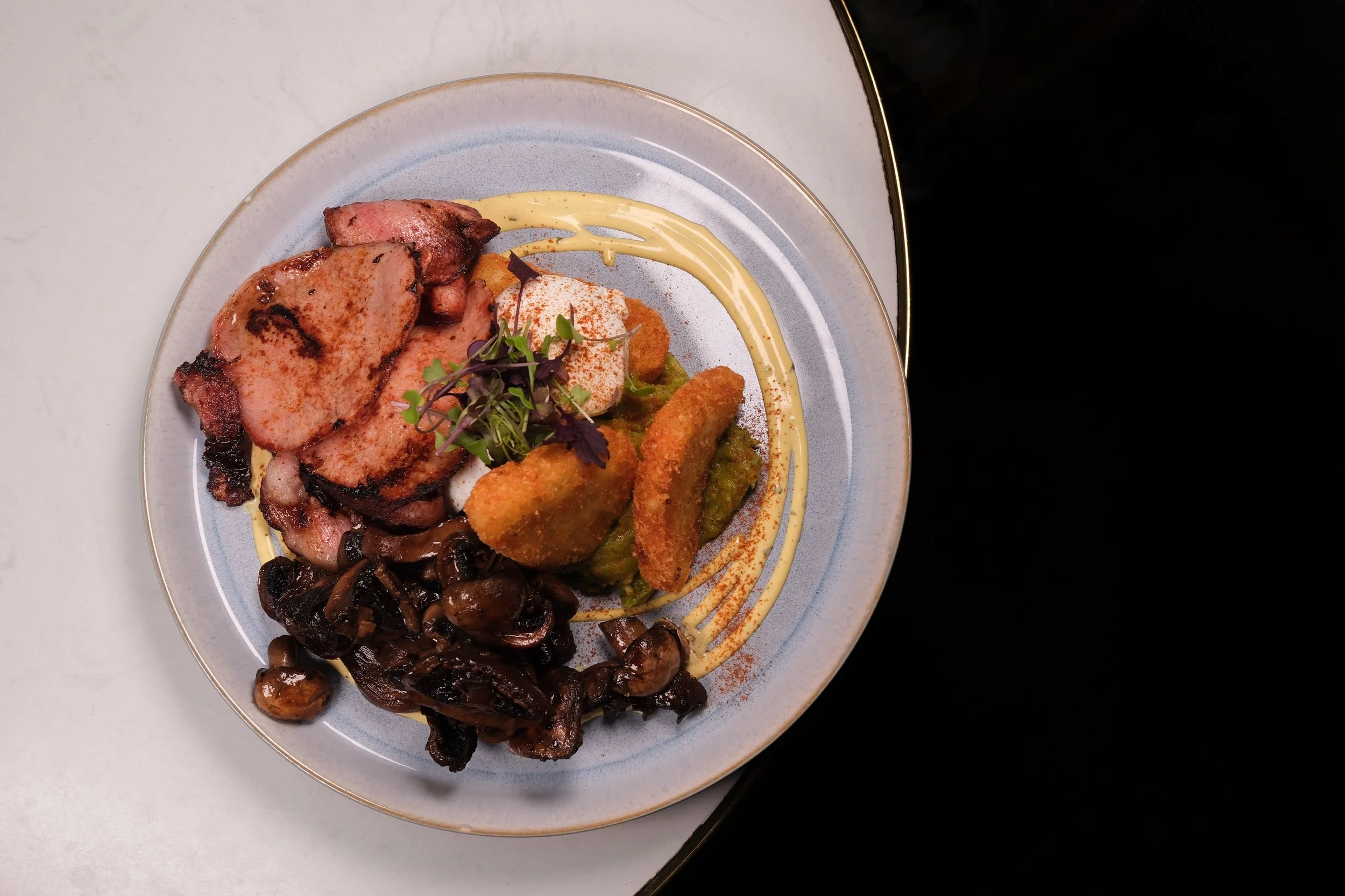 A dinner plate with grilled meat, sautéed mushrooms, fried finger foods with dips, and garnished with microgreens.  Food Photo Co.