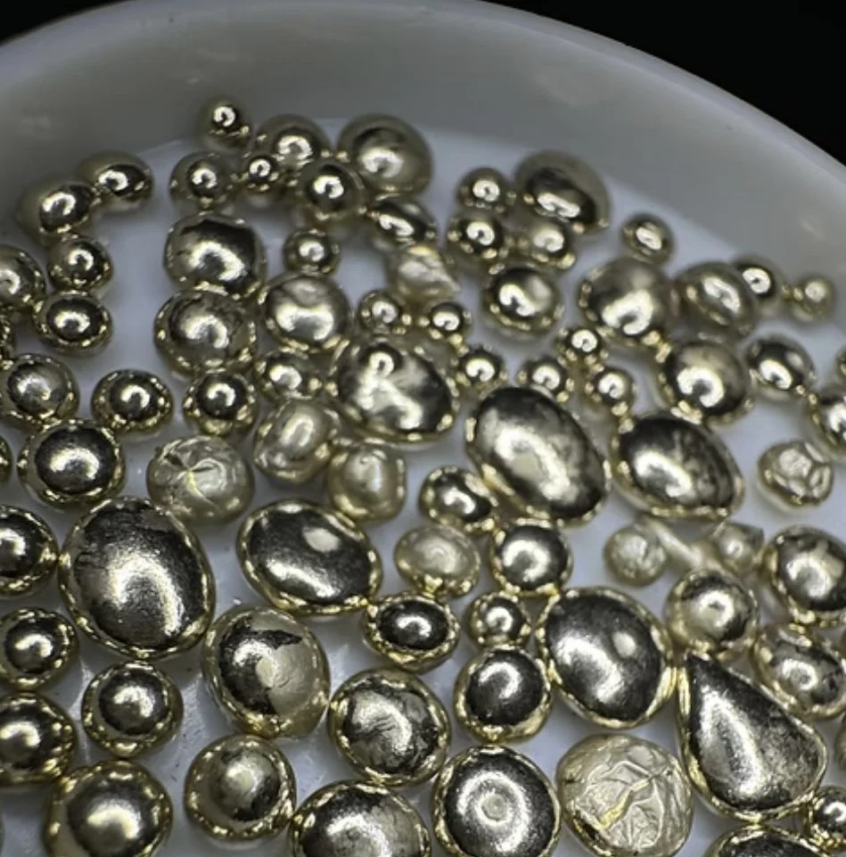 Perle di metallo di varie dimensioni su un piatto bianco.