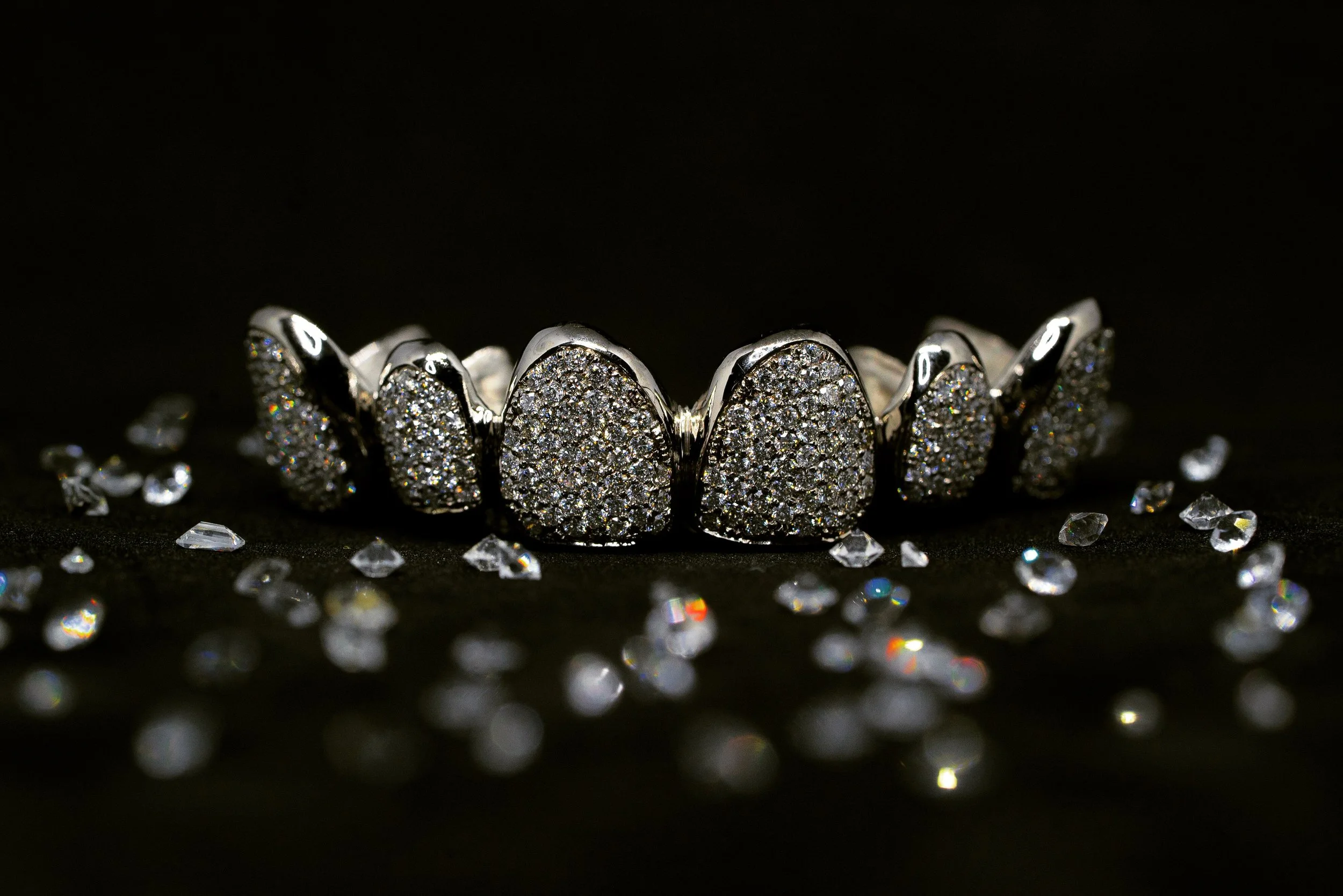 Bracciale da donna in metallo con charms a cuore ricoperti di cristalli, circondato da piccoli cristalli su uno sfondo nero.