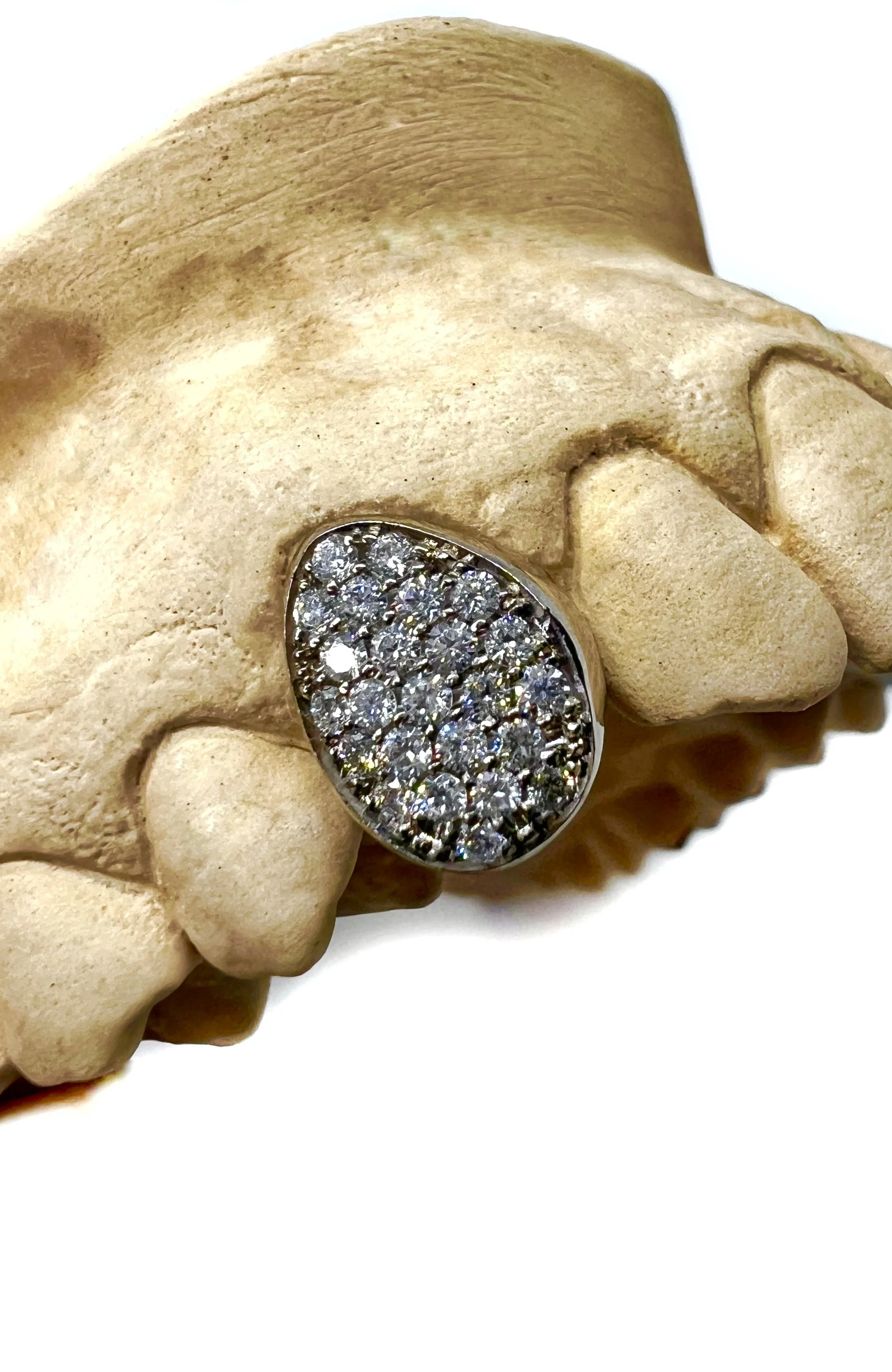 Anello con diamanti incastoniato in argento posato su una scultura di una mano.