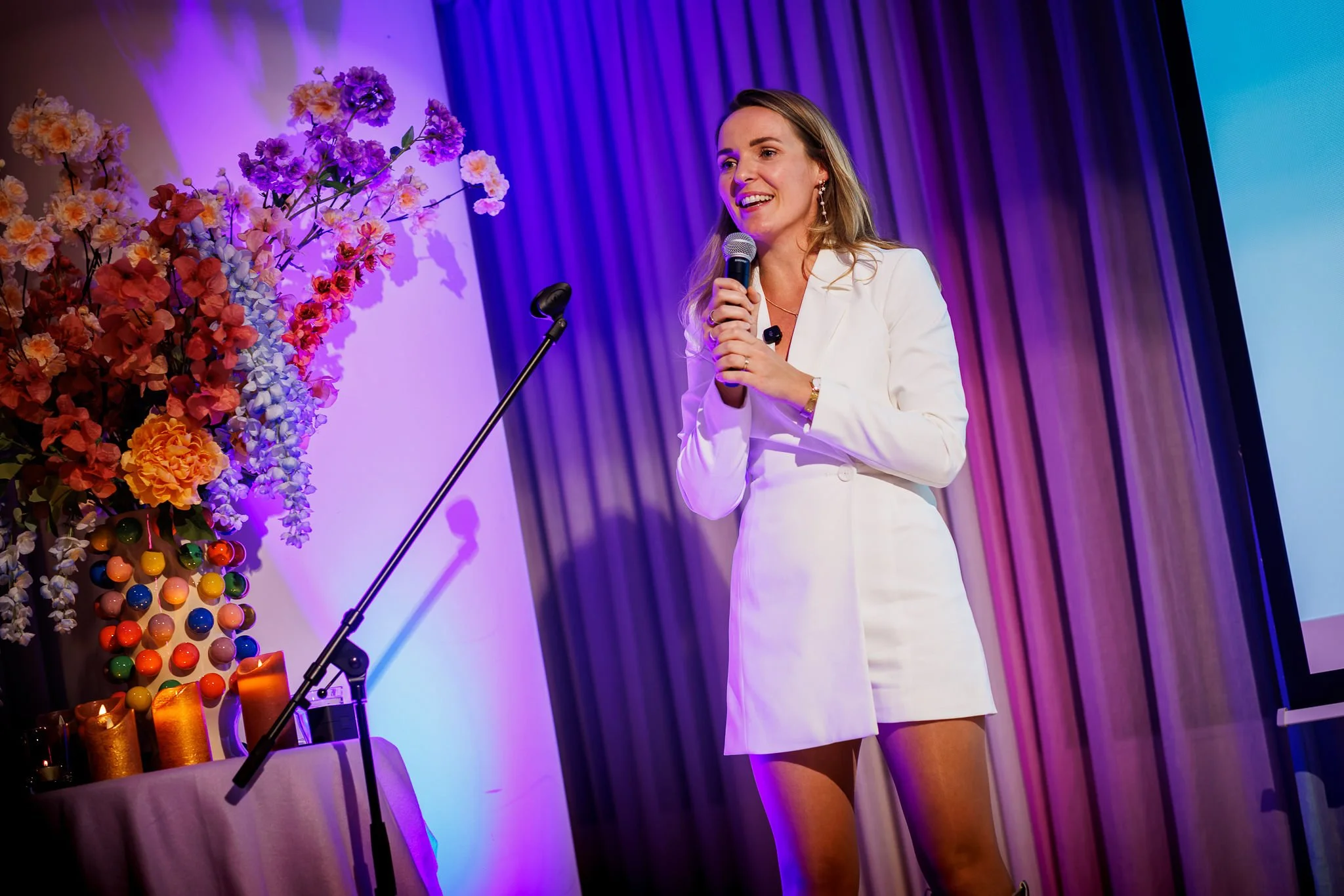 Anke van den Bos spreekt op podium voor een grote groep
