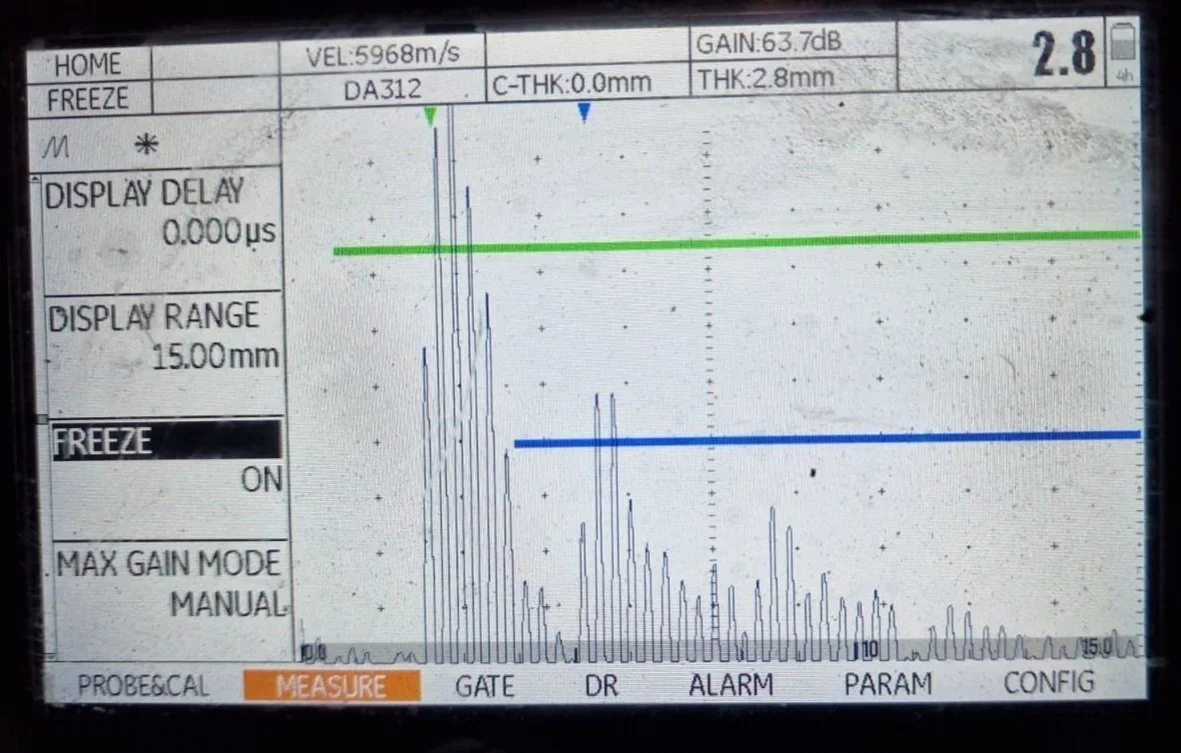Oscilloscope screen showing signal measurements with three horizontal lines marked green, blue, and gray, along with various measurement details and settings.