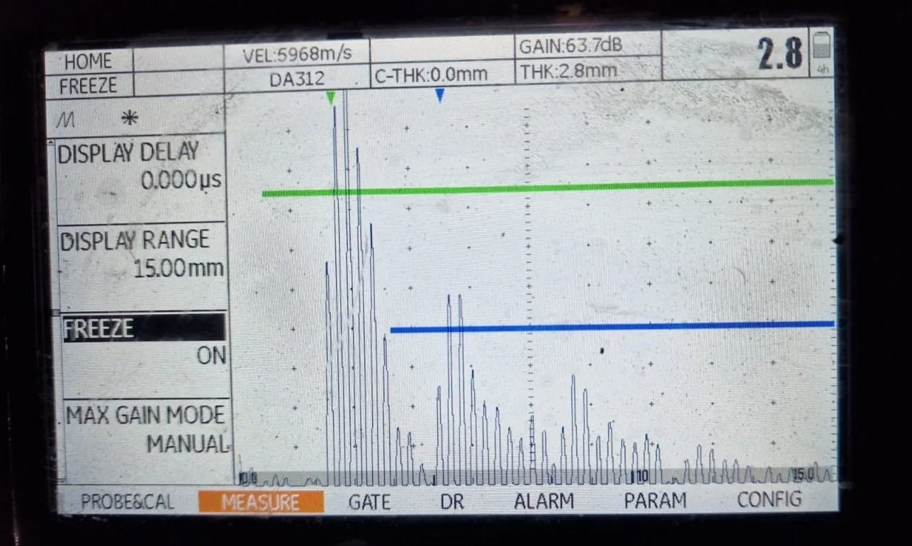 Oscilloscope screen displaying a graph with green and blue horizontal lines, measurement parameters, and a graph of electrical signals.
